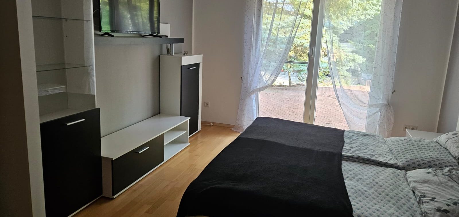 großes Schlafzimmer Schlafzimmer mit Bett, TV, Fenster und modernen Möbeln in neutralen Farben.