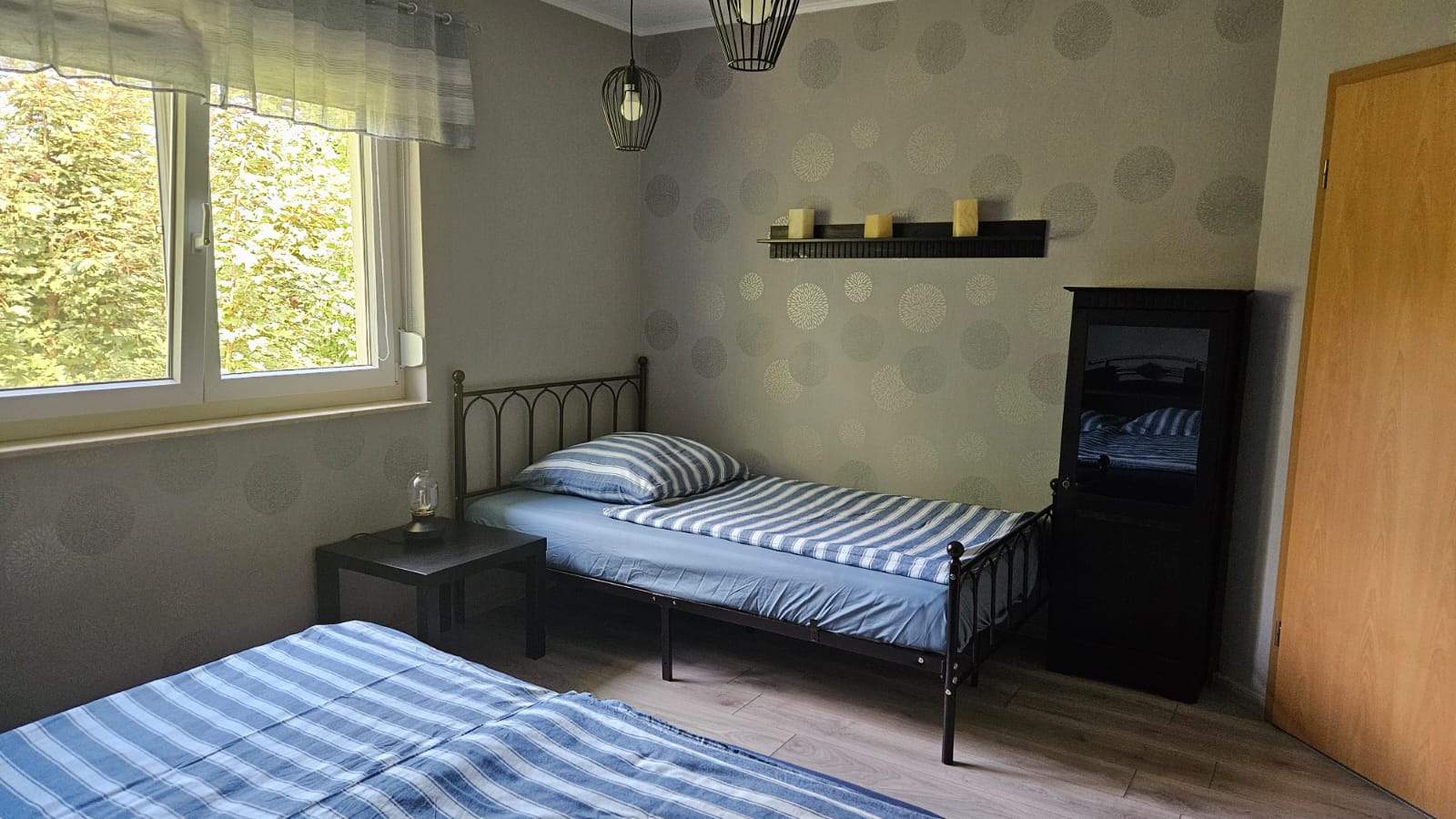 großes Gästezimmer Schlafzimmer mit zwei Betten, Nachttisch, Fenster und schwarzem Schrank.