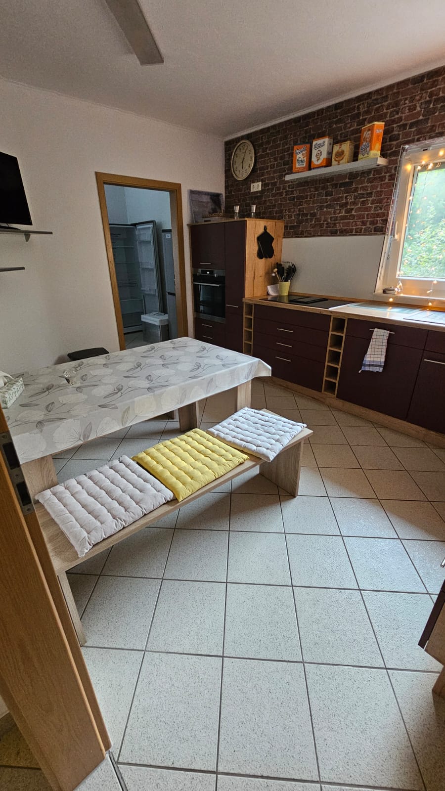 Sitzecke in der Küche Moderne Küche mit Holztisch, Stühlen und Backofen, hellem Licht durch Fenster.