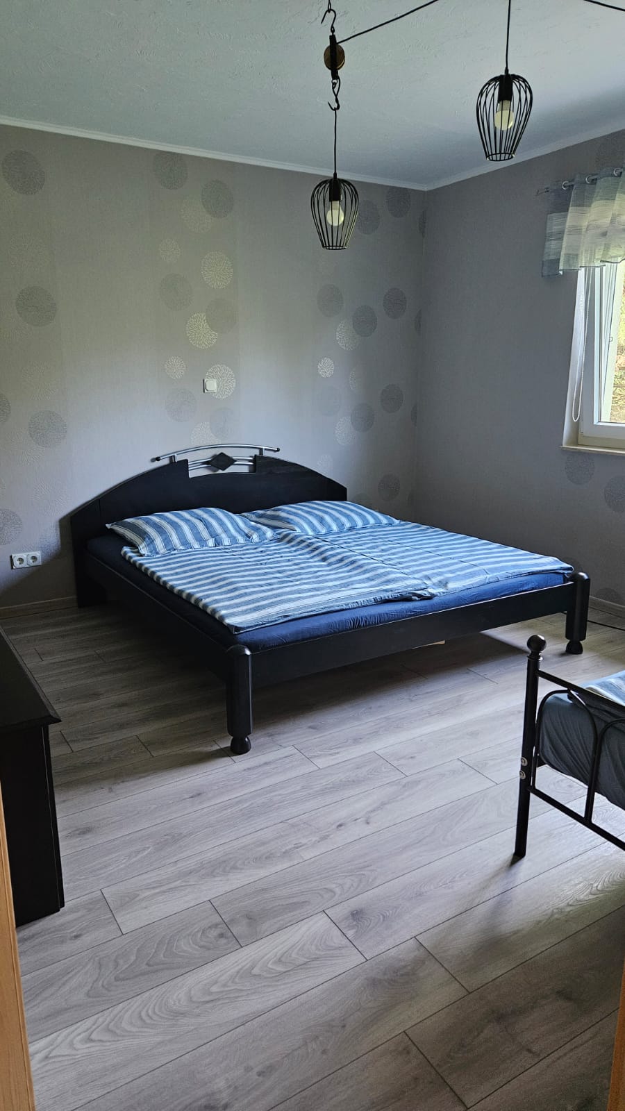 großes Gästezimmer Modernes Schlafzimmer mit einem Bett, Holzdielen und minimalistischem Möbeldesign.